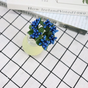 Blue artificial berries in a small ceramic vase on a checkered tablecloth background
