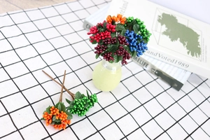 Close-up of artificial colorful berries with green leaves on a plaid decorative cloth