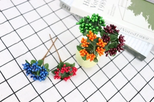 Macro view of colorful artificial berry stems with pearlescent finish and green leaves