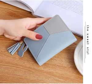 Close-up of light blue and gray bifold wallet with rabbit pendant and tassel detail