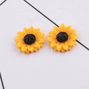 Macro detail of yellow resin daisy charms with black center for DIY hair accessories