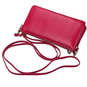 Close-up of magenta lychee grain leather texture and gold zipper on a crossbody bag