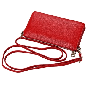 Detail of red pebbled leather crossbody bag showing silver zipper and texture