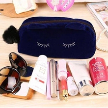 Detail of navy blue cat-ear plush cosmetic bag with lashes embroidery and makeup items