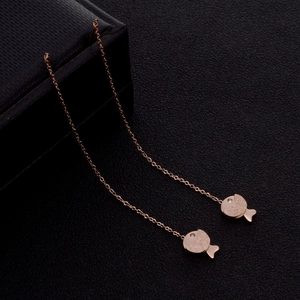 Detail of rose gold fish earrings with matte finish and small diamond on leather box