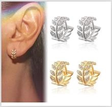Close-up of gold and silver leaf hoop earrings with clear zircon on a model