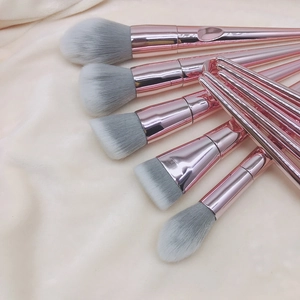 Detail view of 8 professional makeup brushes with rose gold handles on soft beige fabric