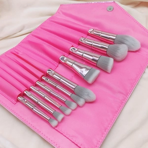 Macro shot of 10 pink makeup brushes with silver metal handles and a roll-up PU leather bag