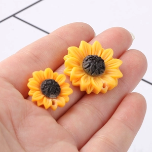 Yellow resin sunflower beads with 1.5mm holes shown in hand for size comparison