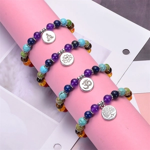 Close-up of four-piece beaded bracelet set featuring tree of life and lotus metal charms