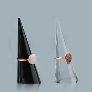 Dettaglio di anelli dorati con pietre rosa e viola su espositori a cono in acrilico