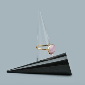 Anello dorato con parte superiore tonda in smalto rosa su espositore a cono chiaro