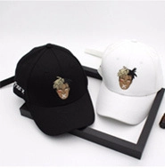 Close-up of black and white embroidered baseball caps with XXXTentacion character portrait