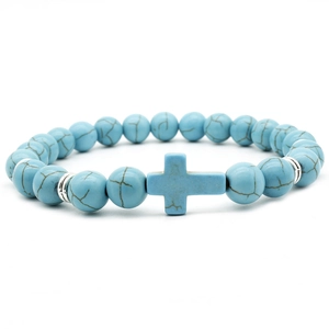 Blue turquoise beaded bracelet with silver spacers and a cross pendant on white background