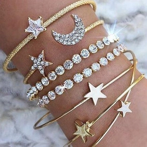 Detail of star and moon multi-layer bracelets in gold finish with white rhinestones