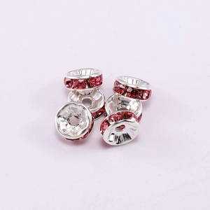 Close-up of silver wheel spacers with pink rhinestones for DIY jewelry making