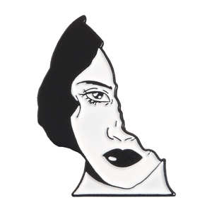 Detail of minimalist black and white enamel brooch with an abstract face design