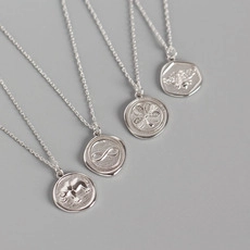 Detailed macro view of S925 silver coin pendants with elephant and bee embossments