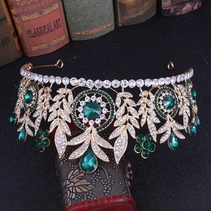 Detailed macro of golden bridal crown with emerald green crystals and leaf motifs
