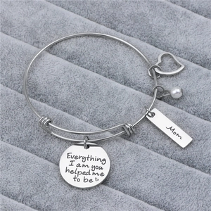 Detail of silver steel bracelet showing engraved Mom tag and sentimental charms