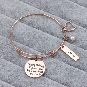 Detailed view of rose gold adjustable bracelet with Mom charm and pearl on grey velvet