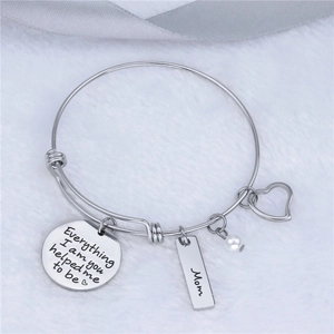 Silver Mother's Day charm bracelet with engraved message on white faux fur background