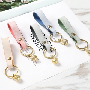 Detail of five assorted colorful leather keychains with gold metal rings and leaf pendants