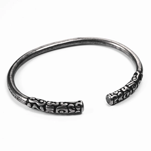 Detailed close-up of silver open cuff bracelet with intricate engraved ends in retro style