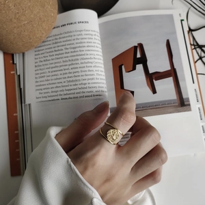 Detail of a gold coin relief ring with double band design worn on a model's finger