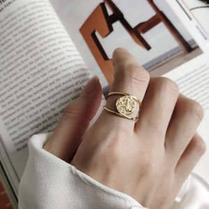 Detail of vintage embossed gold coin open ring on model hand with artistic books