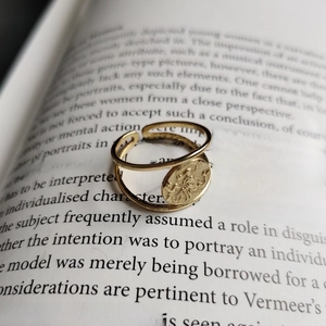 Close-up of golden adjustable coin ring with relief detail on an open book page