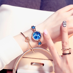 Detail of blue galaxy dial watch with gold star chain strap worn with gold jewelry