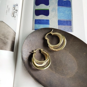 Close-up of gold S925 sterling silver triple hoop earrings on an artistic magazine