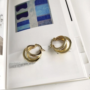 Detail view of triple-layered gold hoop earrings resting on an art magazine background
