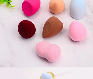 Macro detail of a light blue makeup sponge resting on a metallic gold holder stand