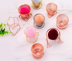 Detailed top view of metal makeup sponge holders in spiral and animal shapes on marble