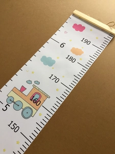 Detail of canvas growth chart featuring wooden hanger and creative cartoon train pattern