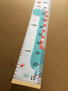 Close-up of canvas height chart with blue dinosaur print and wooden frame details