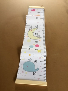 Detail of wooden hanging rod and canvas growth chart with whale and moon patterns