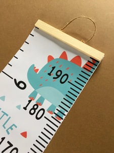 Detail of canvas growth chart with wooden hanger and cute blue dinosaur pattern