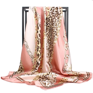 Detail of pink satin scarf featuring leopard print and golden chain patterns on silk texture