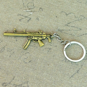 Detailed macro shot of a bronze MP5 submachine gun miniature keychain with metal link chain