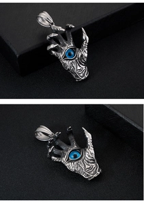 Close-up of vintage steel dragon claw pendant with blue eye stone inlay detail