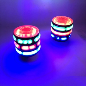 Close-up of two glowing LED spinning tops rotating with vibrant colorful light rings