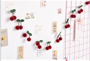 Detail of red plush cherry garland hanging on pink grid wall for room decoration