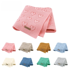 Detailed view of knitted baby blankets featuring hollow heart patterns in eight soft colors