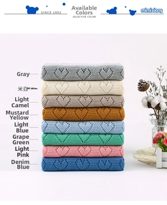 Detail of knitted baby blankets showing hollow heart patterns in eight various soft colors