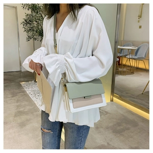 Detail of color-block flap crossbody bag with accordion structure and chain strap