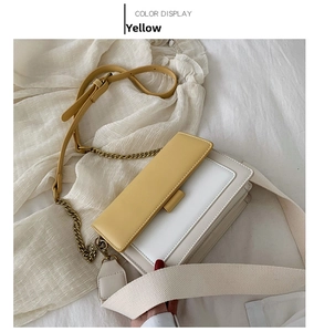 Detail of yellow and white crossbody bag with dual straps on white fabric background