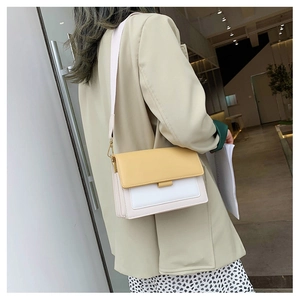 Detailed view of tricolor crossbody bag with yellow flap and wide textile strap on model